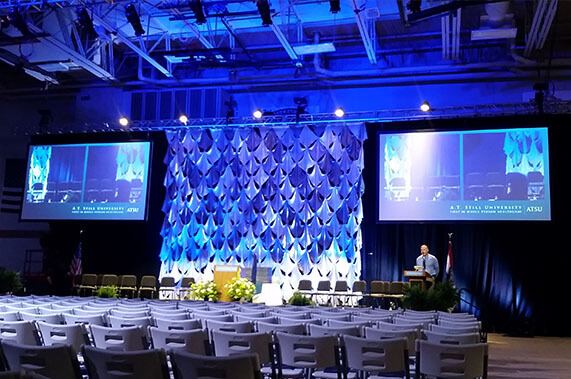 two projector screens and a blue backdrop at a graduation ceremony