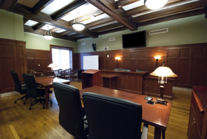 small courtroom with a mounted monitor above the judge's stand