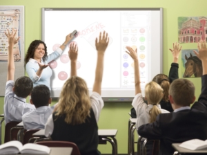 children in a classroom raise hands to answer question