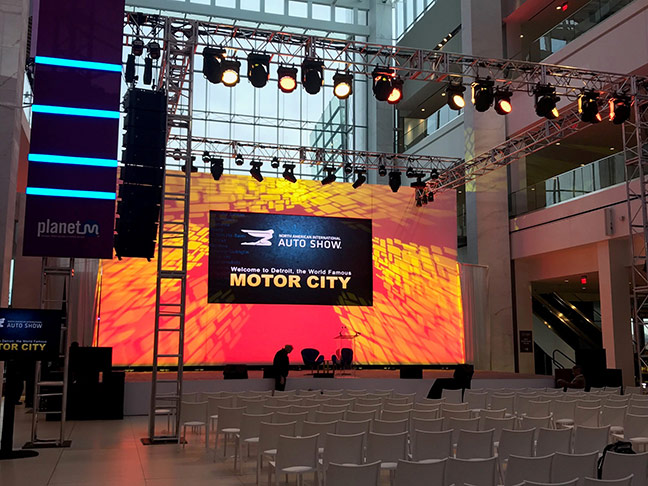 large orange backdrop, display, and lights at an auto show