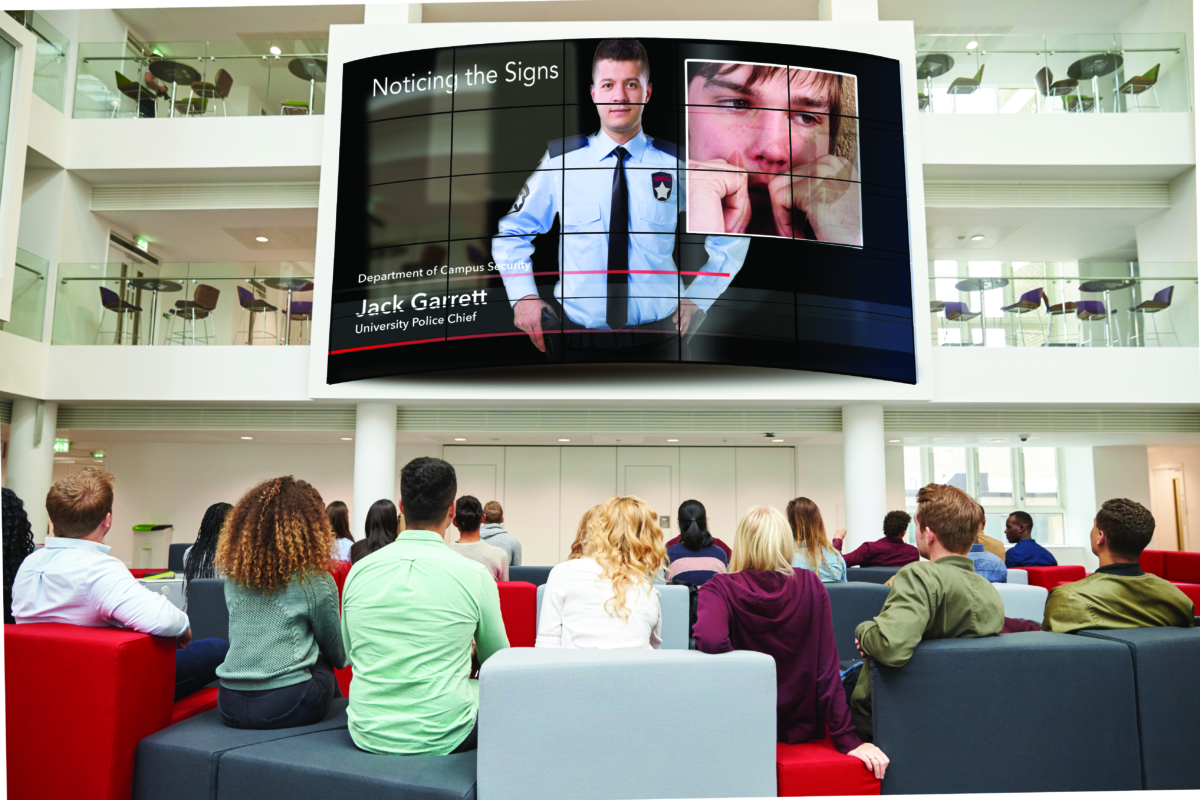 Students watching big screen in university atrium, back view