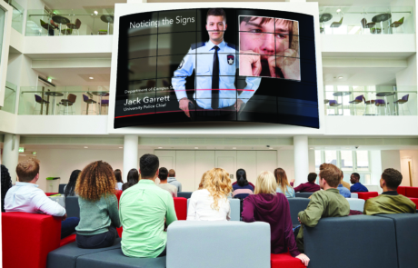 Students watching big screen in university atrium, back view LG Business Solutions