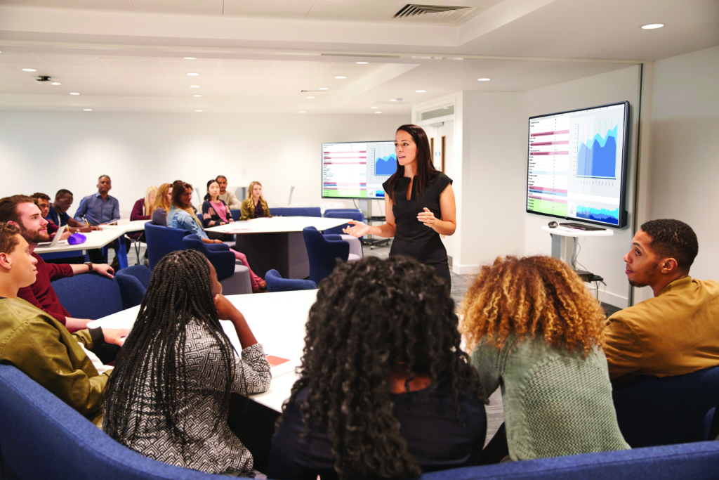 woman leading a class with a tech presentation screen