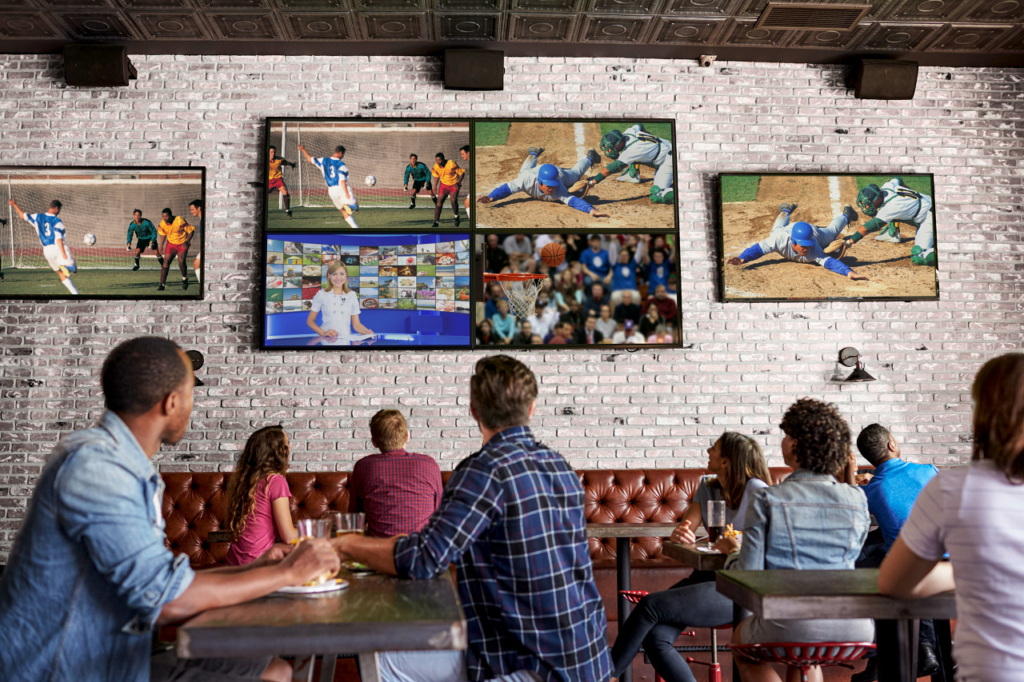 people watching many different sports on TVs at a bar