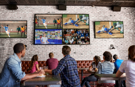 people watching many different sports on TVs at a bar