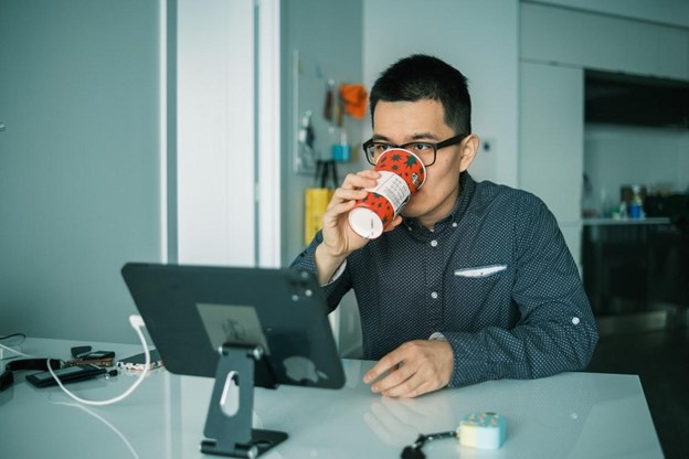 man drinking coffee looking at ipad