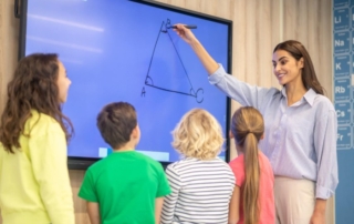 Teacher using interactive smartboard with children watching attentively Ask ChatGPT