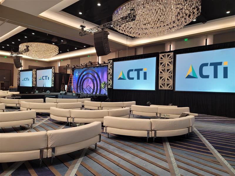 MP Productions landing page header. This is a photo of a live event with multiple screens with CTI logos, several round couches at a live event