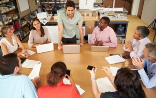 group gathered around table with laptops and smartphones