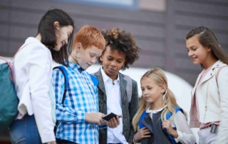 Children standing outside looking at smartphone together