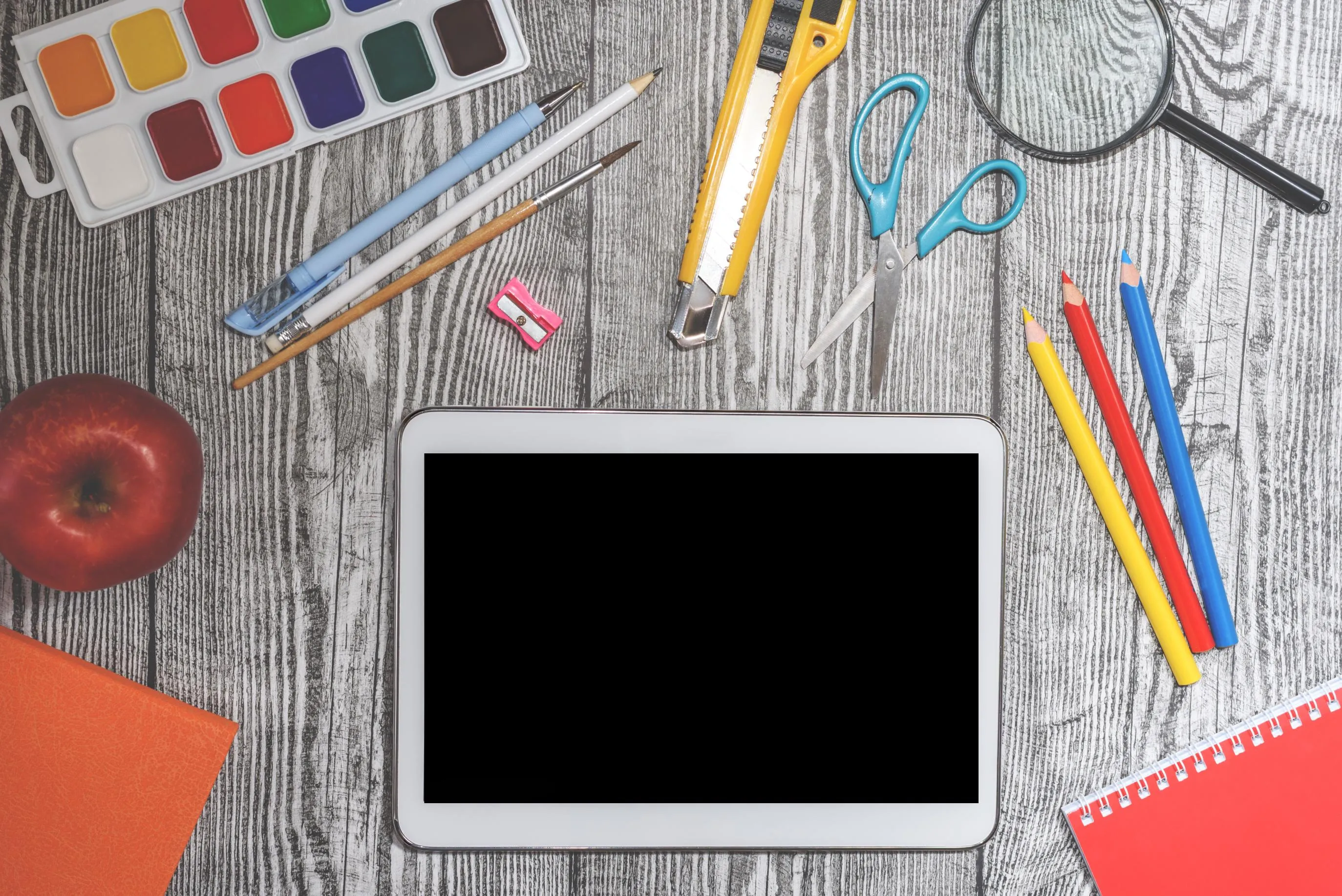 tablet on desk surrounded by school supplies