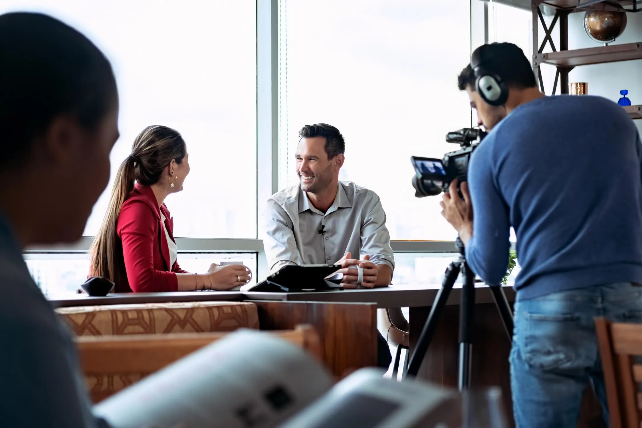 Makeup artist and producer preparing man on camera for filming