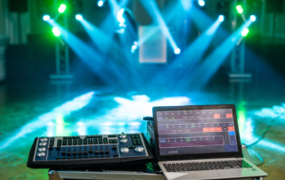laptop and lighting console controlling colored stage spotlights