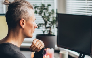 person sitting at desk looking at dual computer monitors