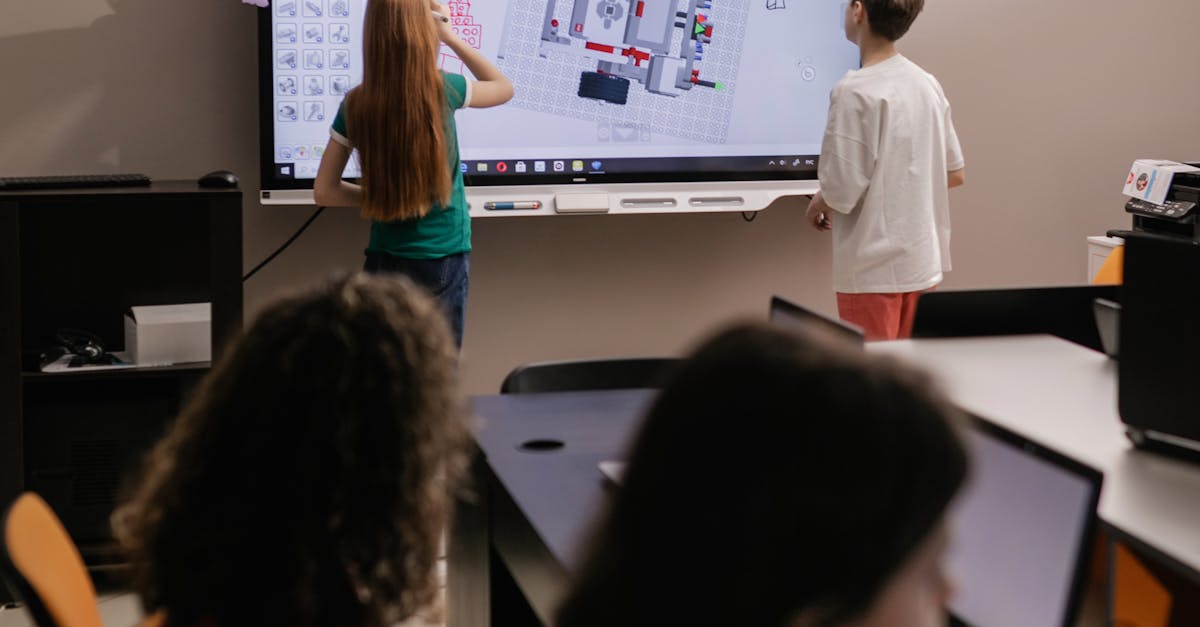 two students drawing on a classroom interactive whiteboard touchscreen