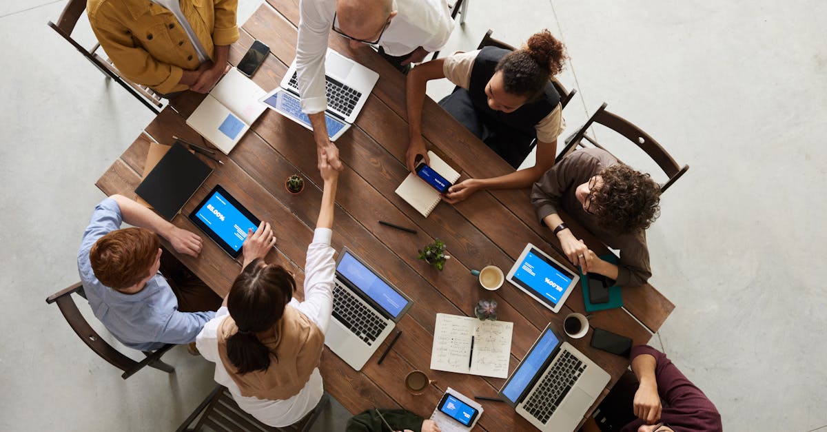 overhead view of team around wooden table with laptops and tablets