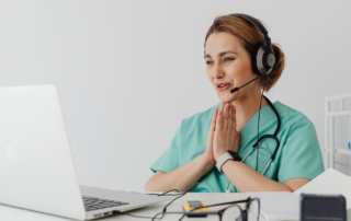 female doctor wearing headset on telehealth video call with laptop