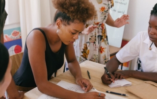 students writing in notebook at table