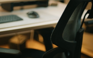 mesh office chair with keyboard monitor and mouse in background