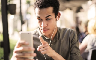 young man pointing at smartphone with earbuds