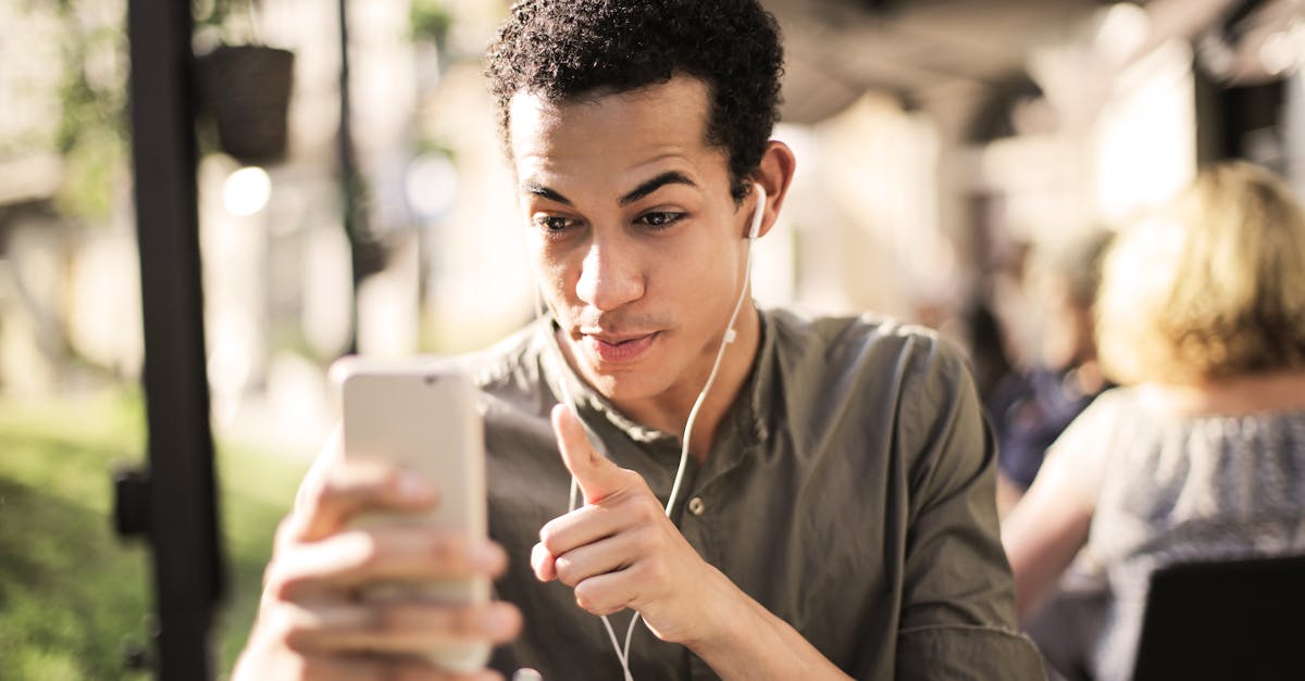 young man pointing at smartphone with earbuds