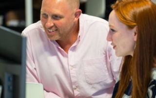 two colleagues smiling at a monitor