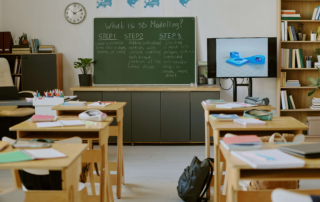 classroom with 3d modeling display on monitor next to chalkboard