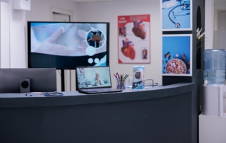 medical office desk with laptop and wall screen display