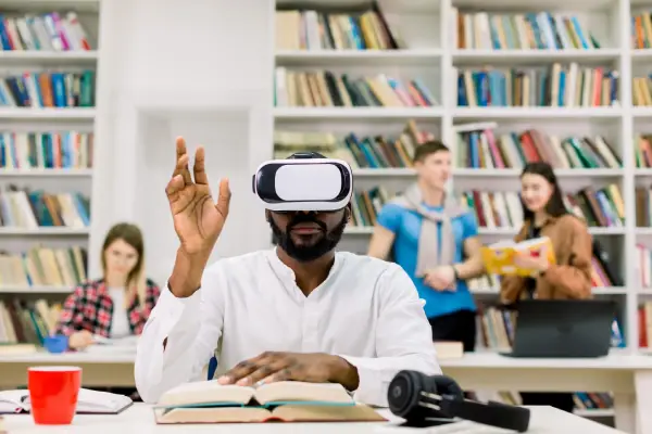 man wearing vr headset in library with laptop headset visible