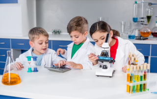 children doing science experiment with calculator and microscope