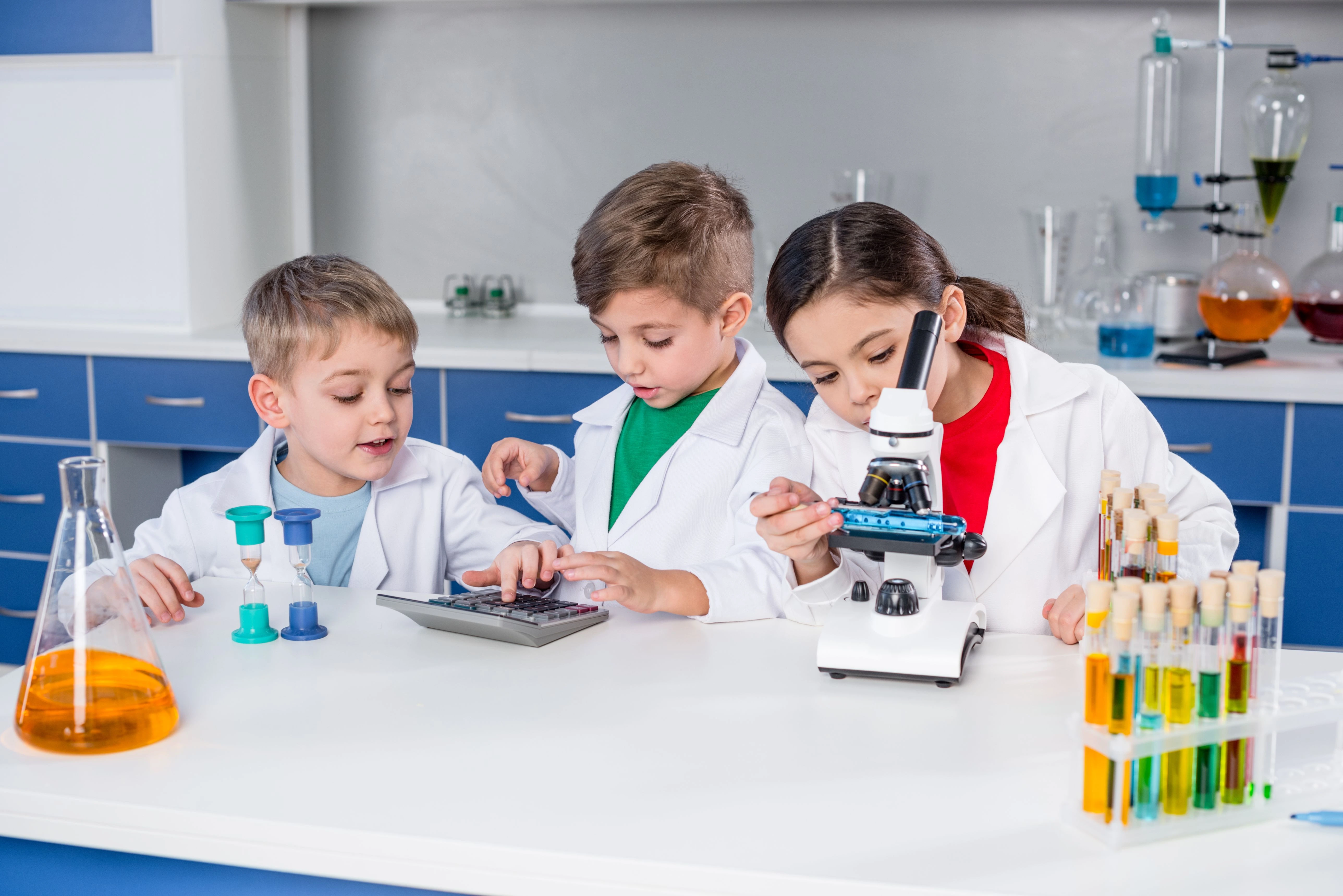 kids-in-white-coats-using-microscope-and-calculato-2024-11-18-06-42-55-utc (1) children doing science experiment with calculator and microscope