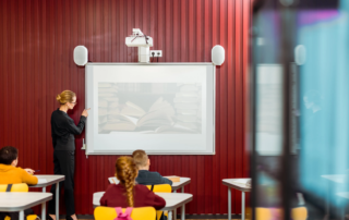 Teacher pointing at screen with projector mounted above whiteboard