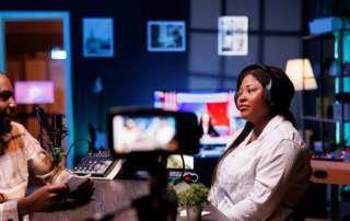 two podcasters speaking into microphone with DSLR camera and studio monitors