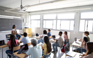 classroom of students with laptops and teacher