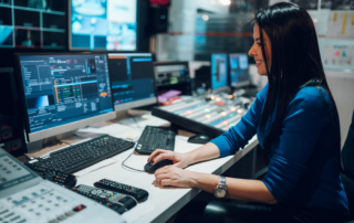 woman at control desk operating multiple monitors in broadcast room