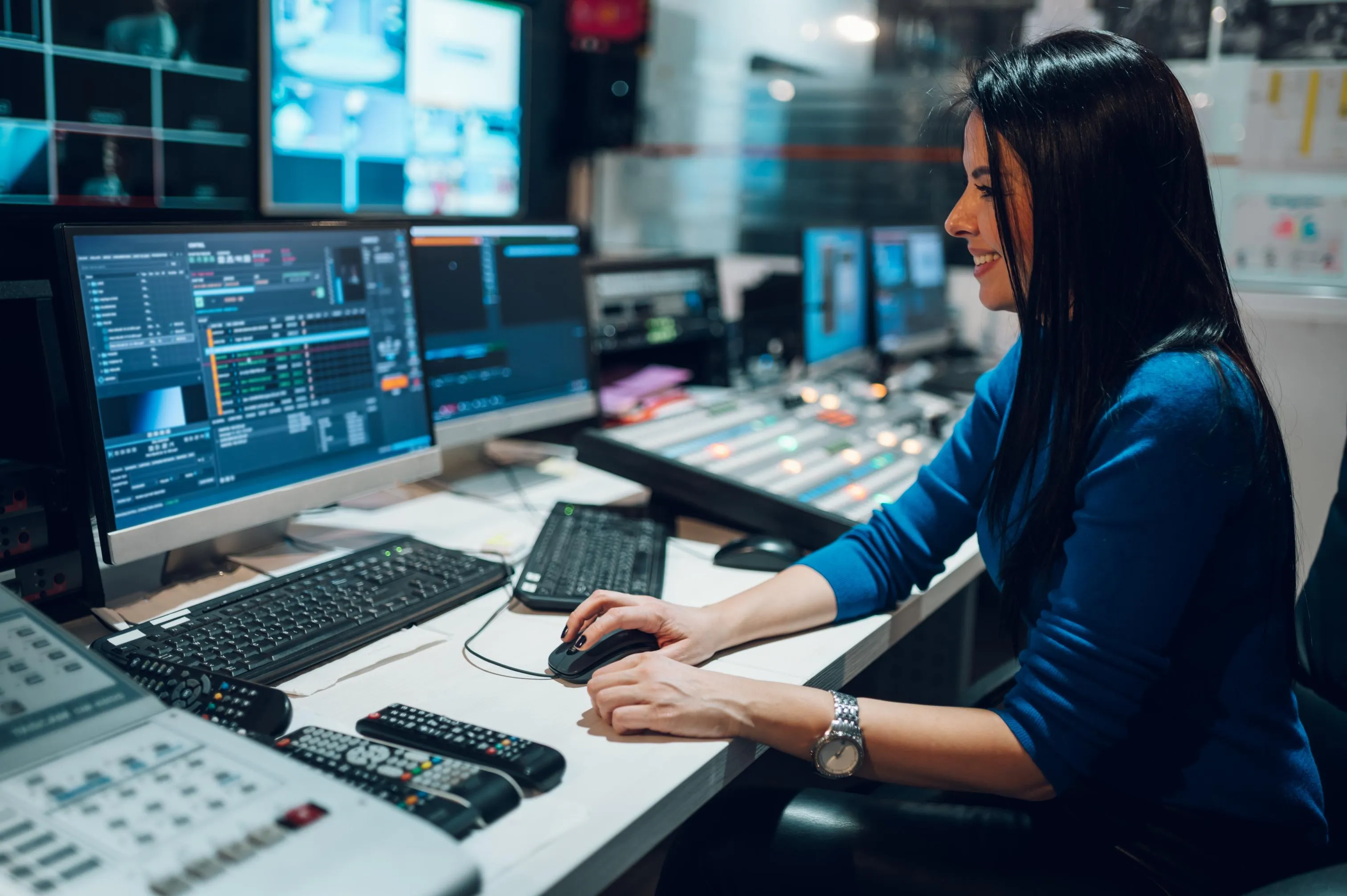 middle-aged-woman-using-equipment-in-control-room-2023-11-27-05-29-31-utc woman at control desk operating multiple monitors in broadcast room