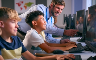 teacher guiding students on desktop monitors