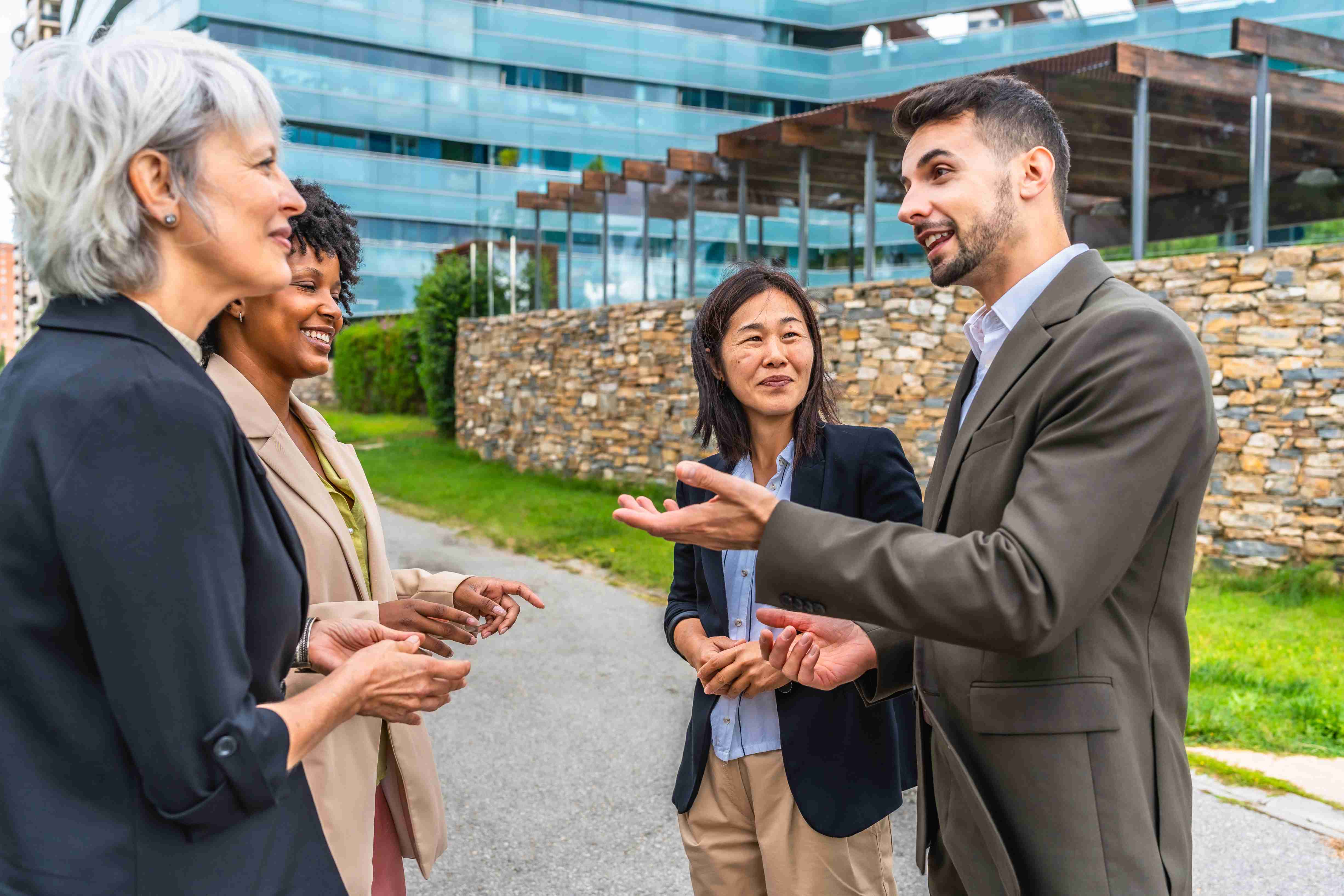 Group of adults having conversation outdoors near office building