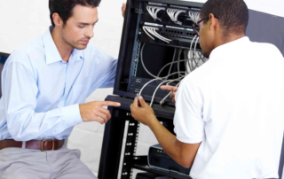 two people working on server rack with cables and equipment