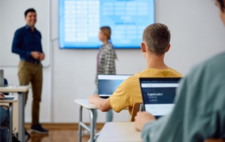 students using laptops in classroom during presentation