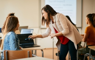 teacher helping student with coding on laptop