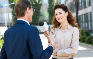 Woman interviewing man outdoors using handheld microphone