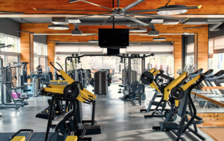 gym with multiple workout machines and ceiling monitor