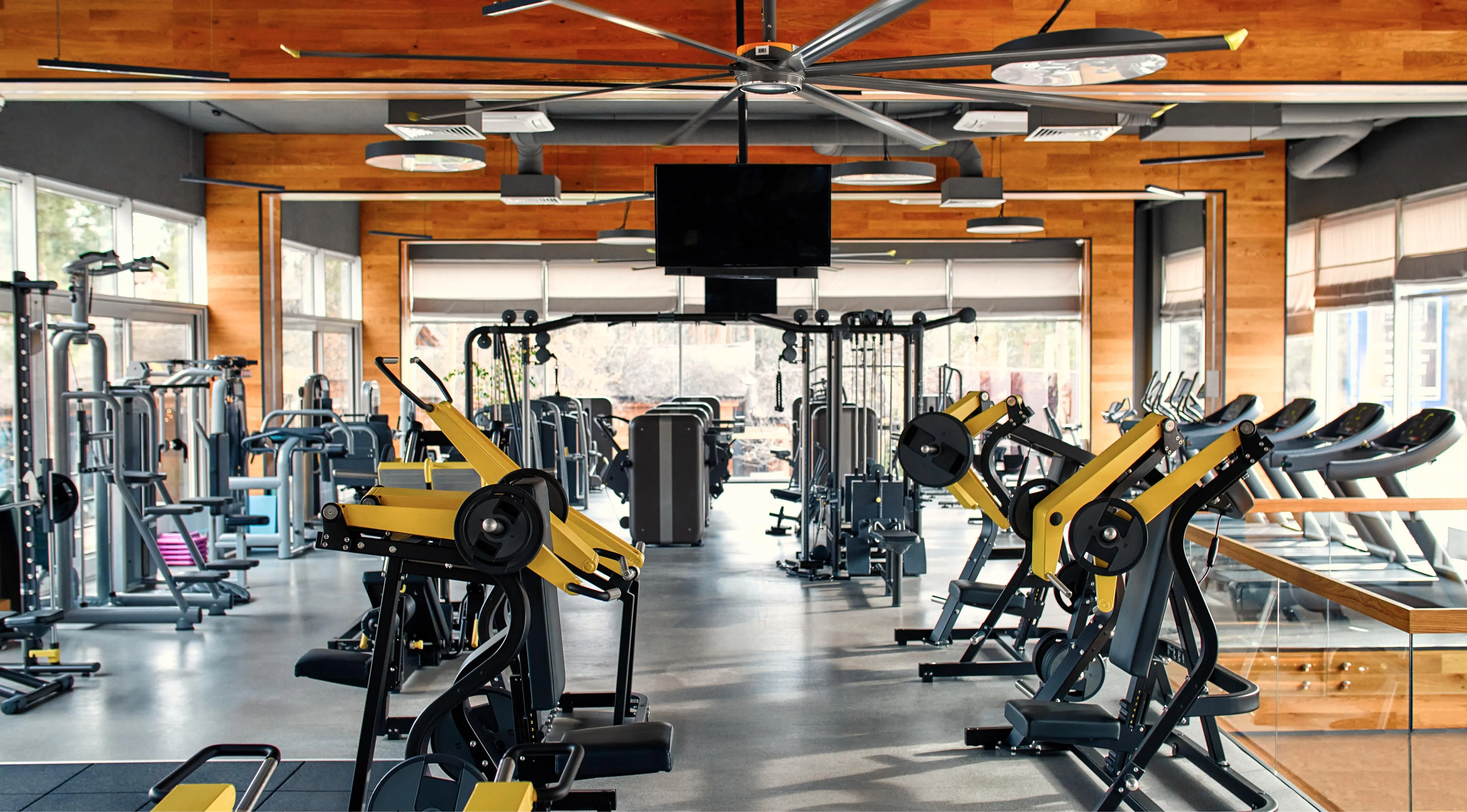 gym with multiple workout machines and ceiling monitor