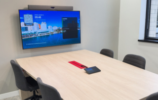 boardroom table with wall mounted display on green wall device monitor