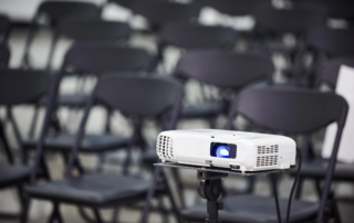 projector on tripod in front of folding chairs