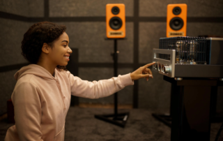woman adjusting audio amplifier in studio with speakers