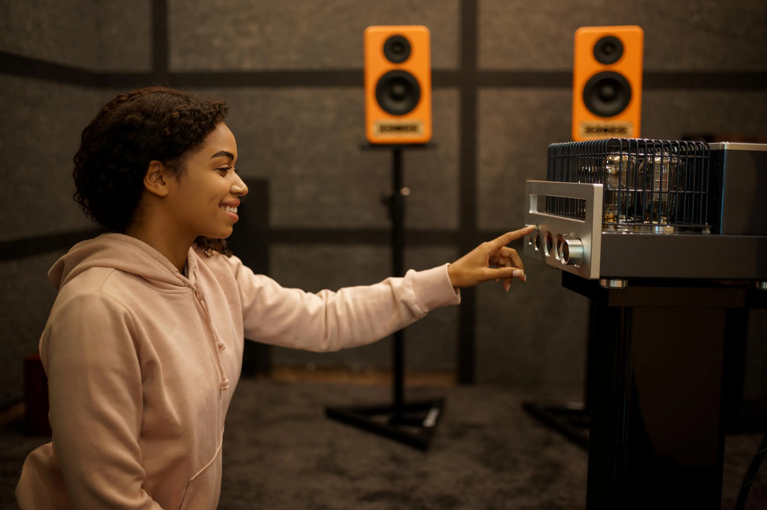woman adjusting audio amplifier in studio with speakers