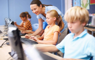 children in computer lab using desktop monitors and keyboards