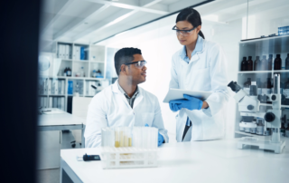 scientists in lab using tablet near microscope